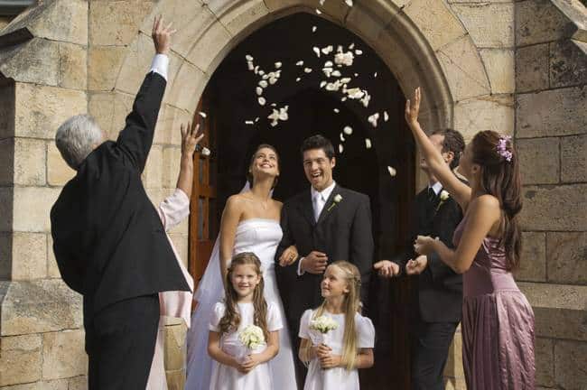 throwing flower petals over bride and groom