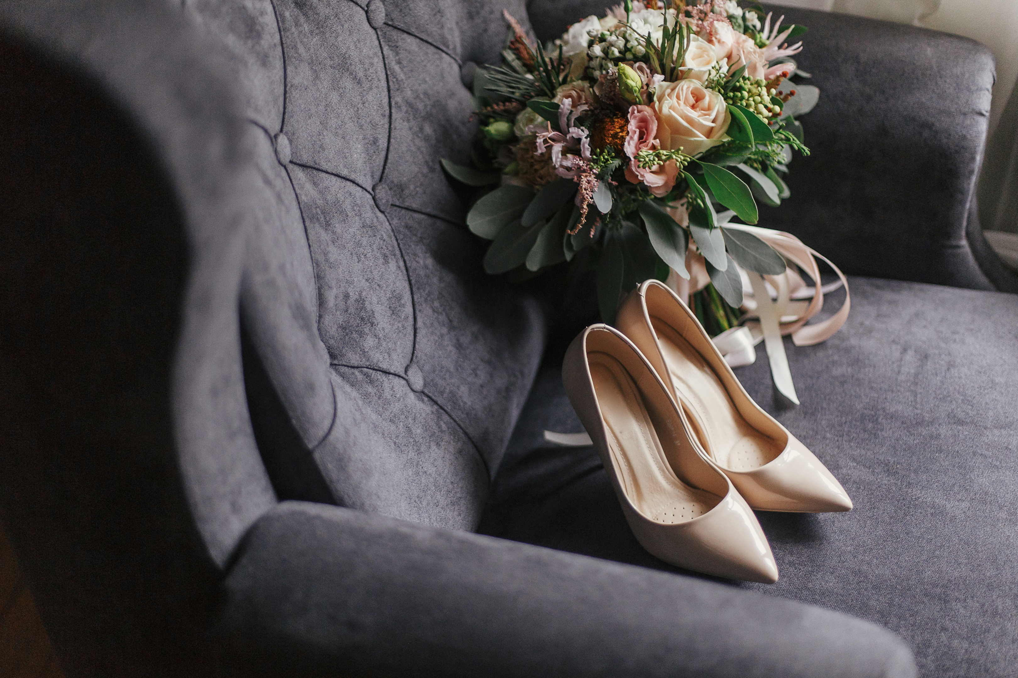 Wedding shoes and bouquet on gray furniture