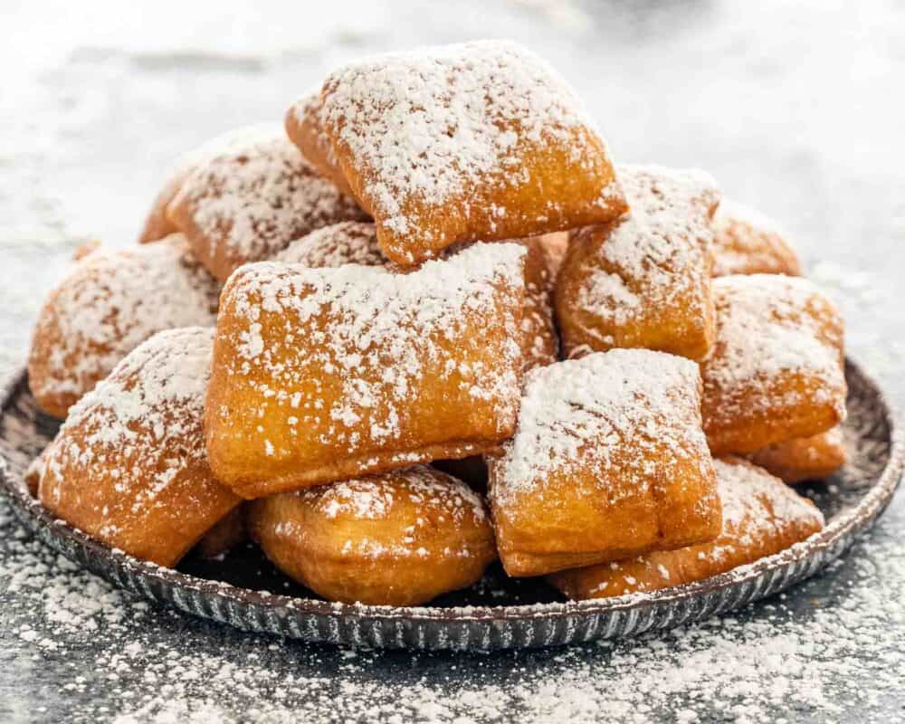 a few beignets with powdered sugar on a plate.