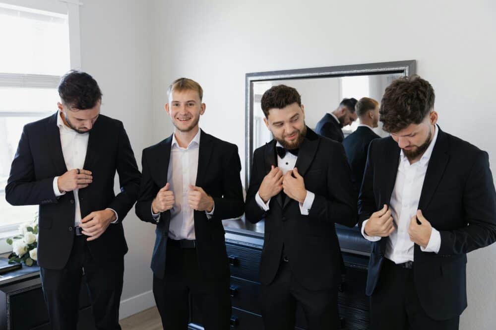 Groomsmen Attire Tips for All Types of Destination Weddings 10 Free Four men in suits preparing for a formal event indoors. Stock Photo