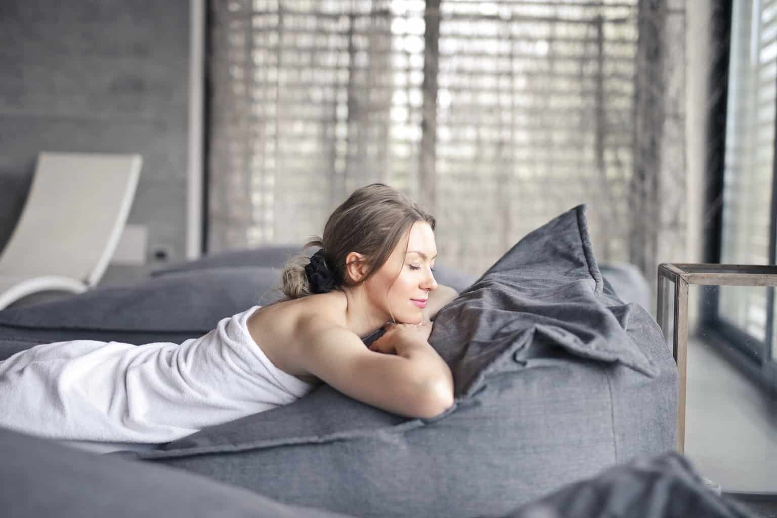 Free Woman in White Tank Top Lying on Gray Bed Stock Photo