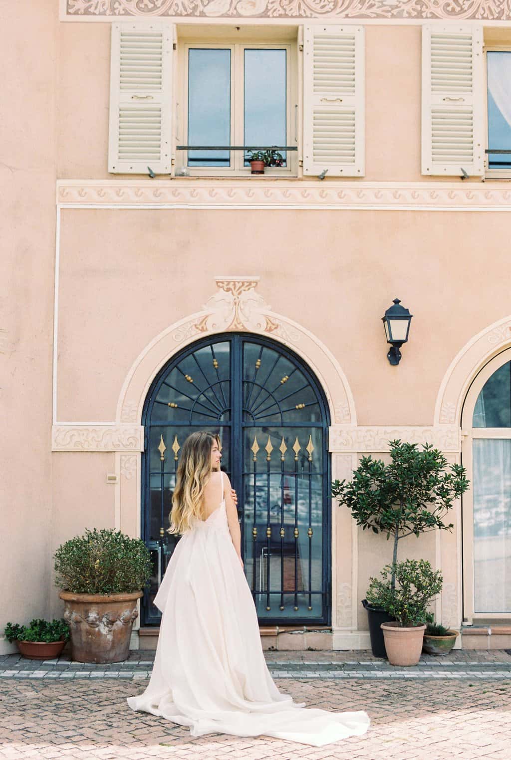 Free Woman in White Dress Standing in Front of a Black Metal Door Stock Photo