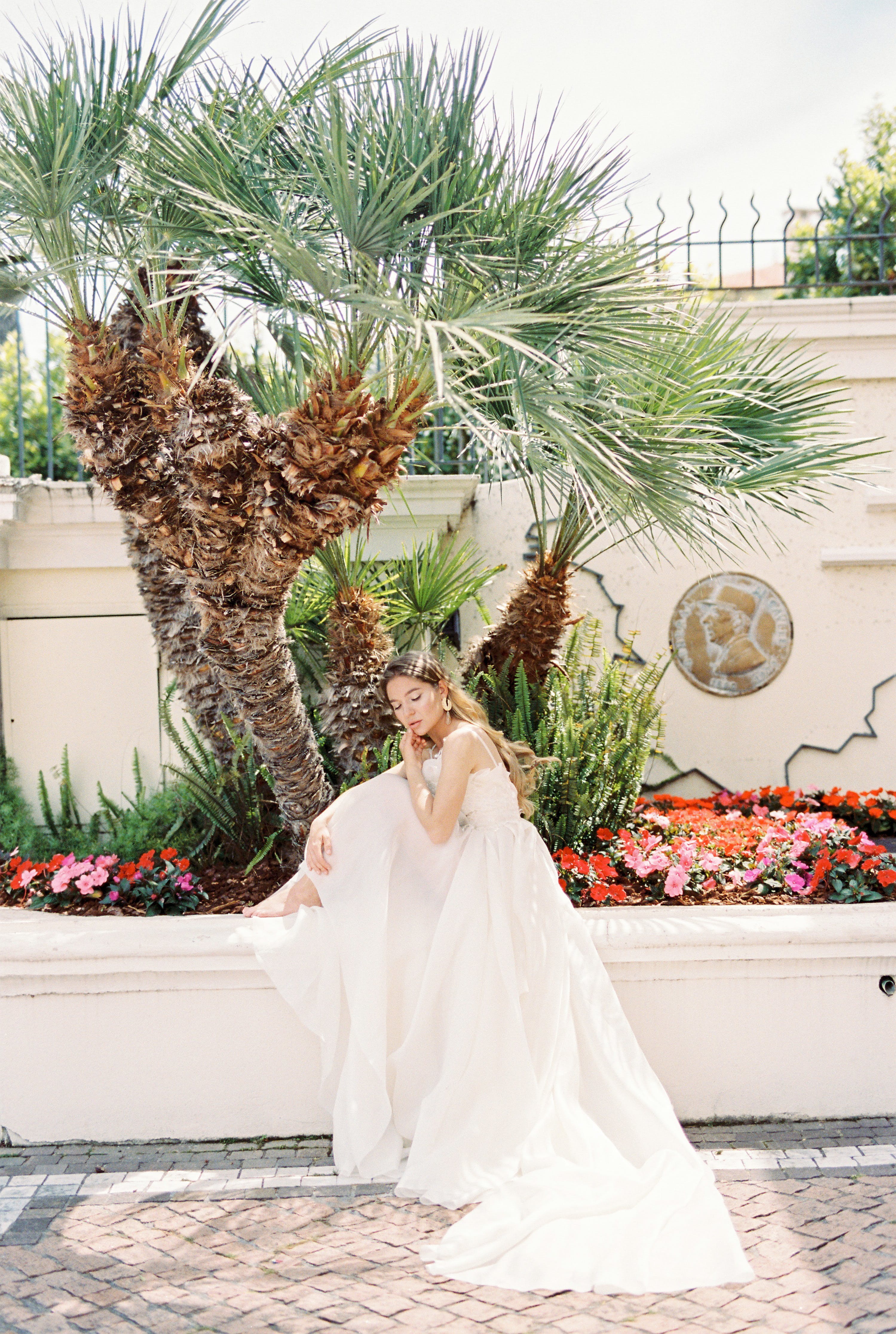 Free Woman in White Wedding Dress Sitting Near Palm Trees Stock Photo