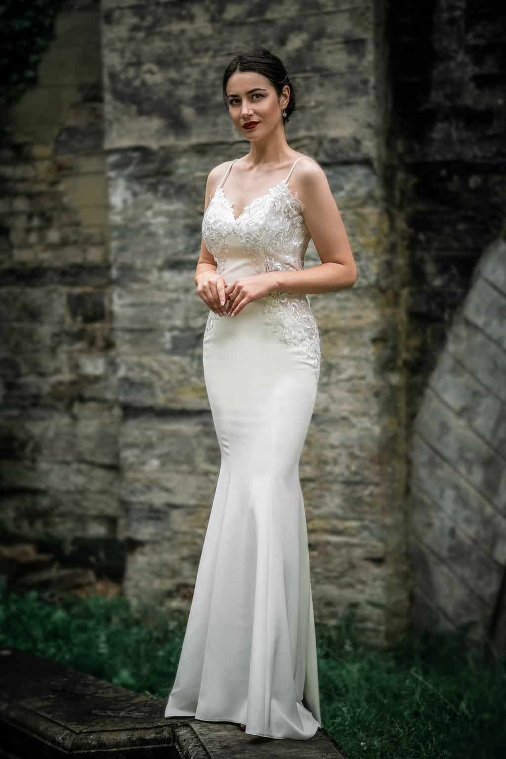 Free A Woman in White Wedding Dress Standing Near Brick Wall Stock Photo