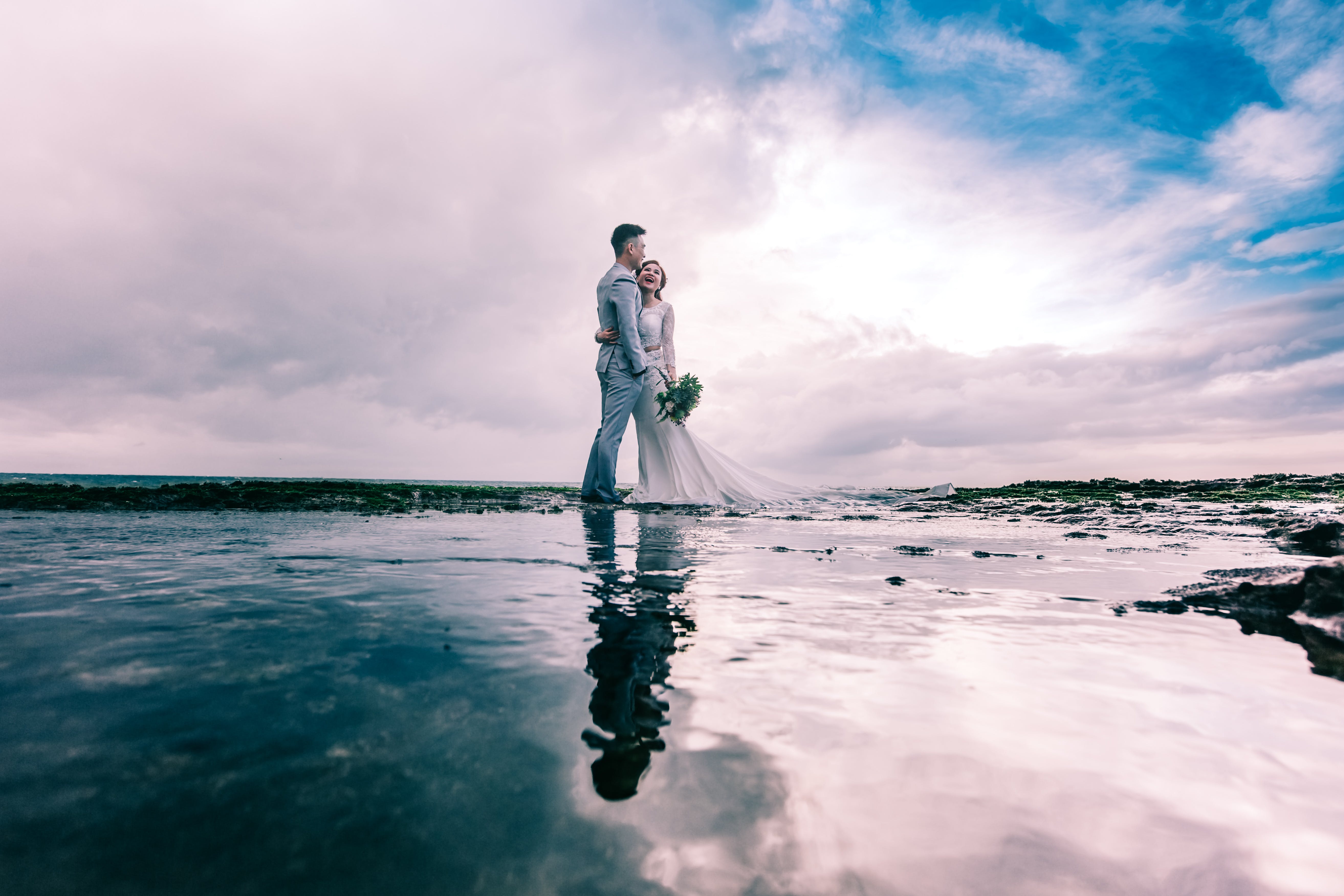Free Man in Gray Dress Suit Jacket Embraces Woman Wearing Wedding Gown Stock Photo