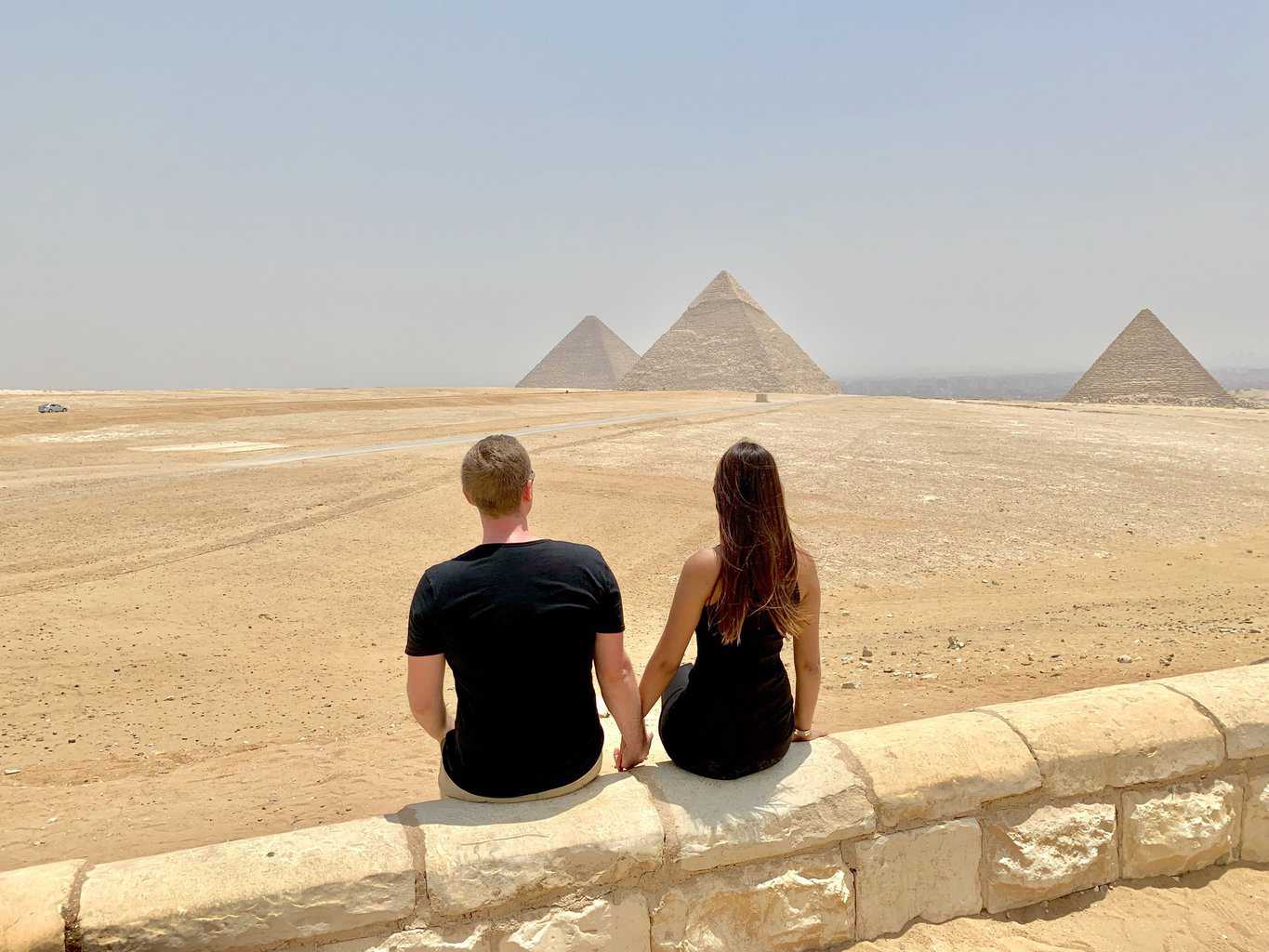 man and woman sitting on concrete wall during daytime