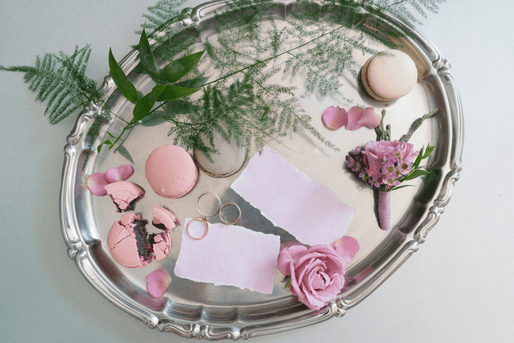 silver platter with wedding rings, boutonniere and macarons