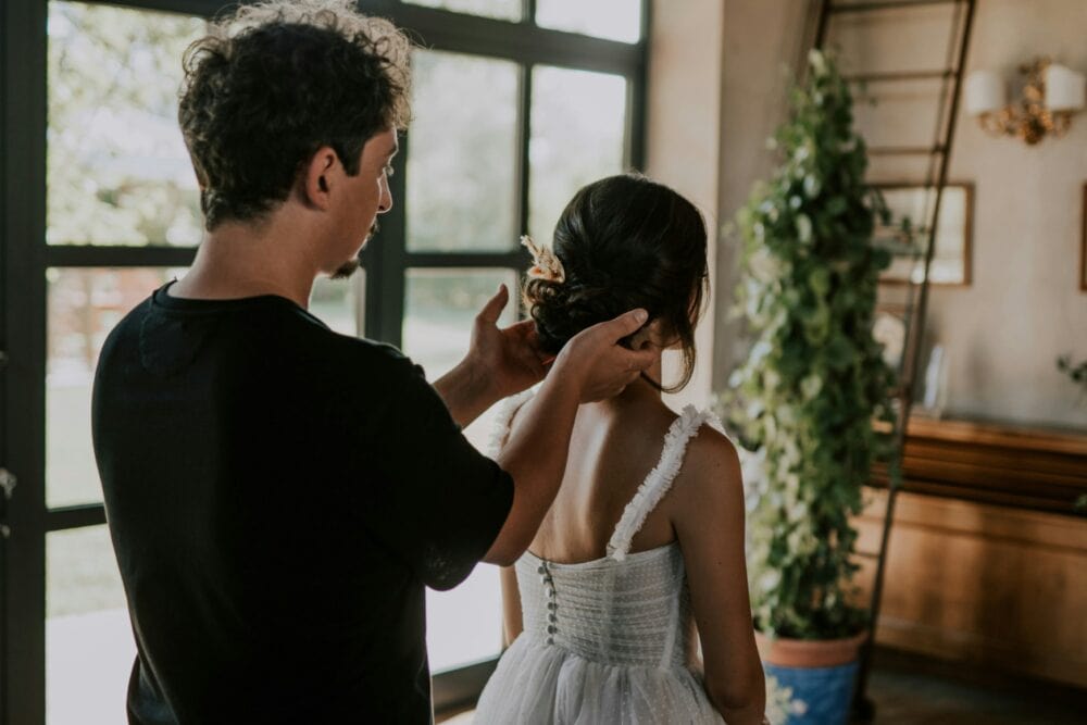 A man helping a woman put on her wedding dress